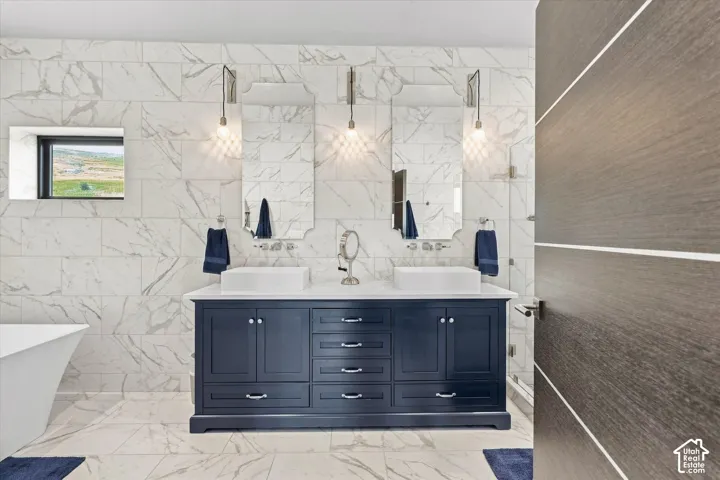 Luxurious dual-vanity bathroom featuring a navy blue cabinetry base with ample storage, polished stone countertops, and chrome fixtures