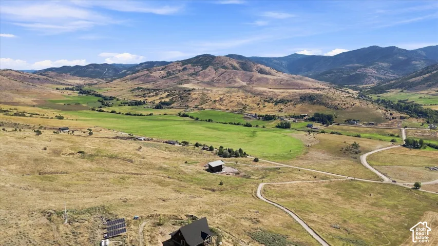 Expansive land featuring a winding driveway, solar panel array, and mountainous backdrop
