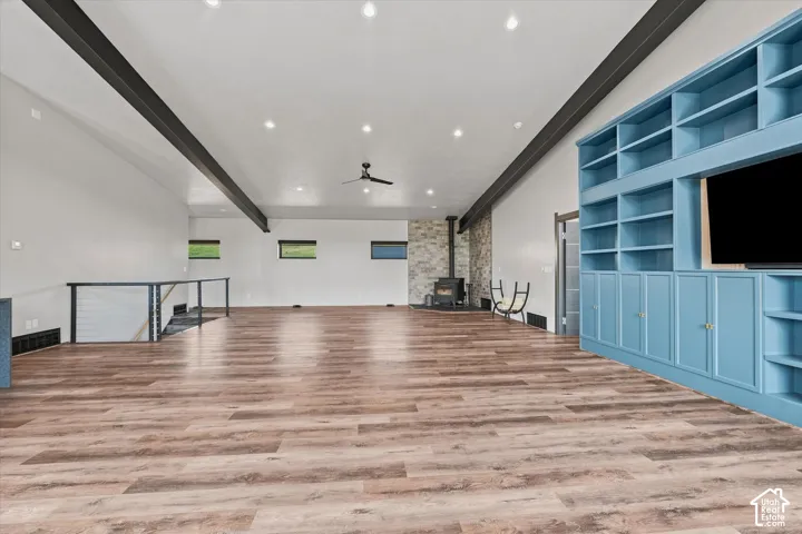 Expansive open-concept loft featuring wood-finish flooring throughout, recessed ceiling lighting, and exposed structural beams