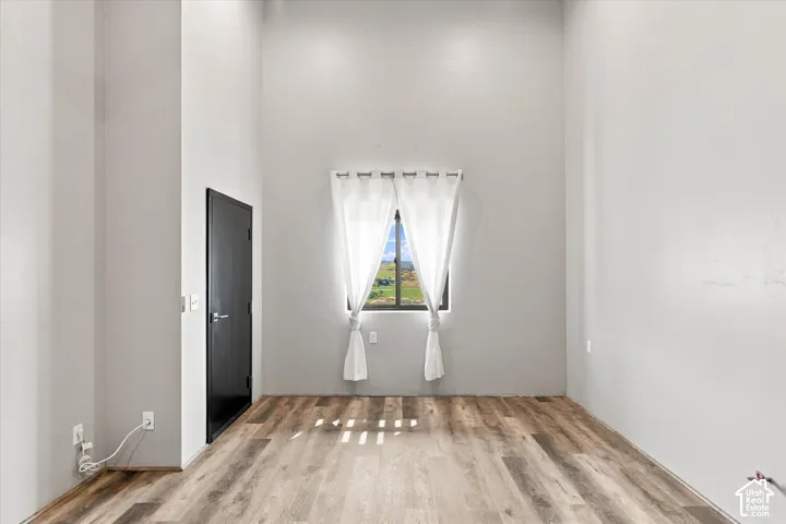 Bright, light-filled room featuring wood-finish flooring, clean white walls, and recessed ceiling lighting