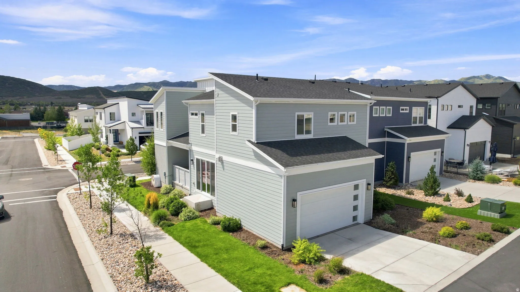 Modern exterior architecture featuring light gray siding, a black shingle roof, and a white paneled garage door