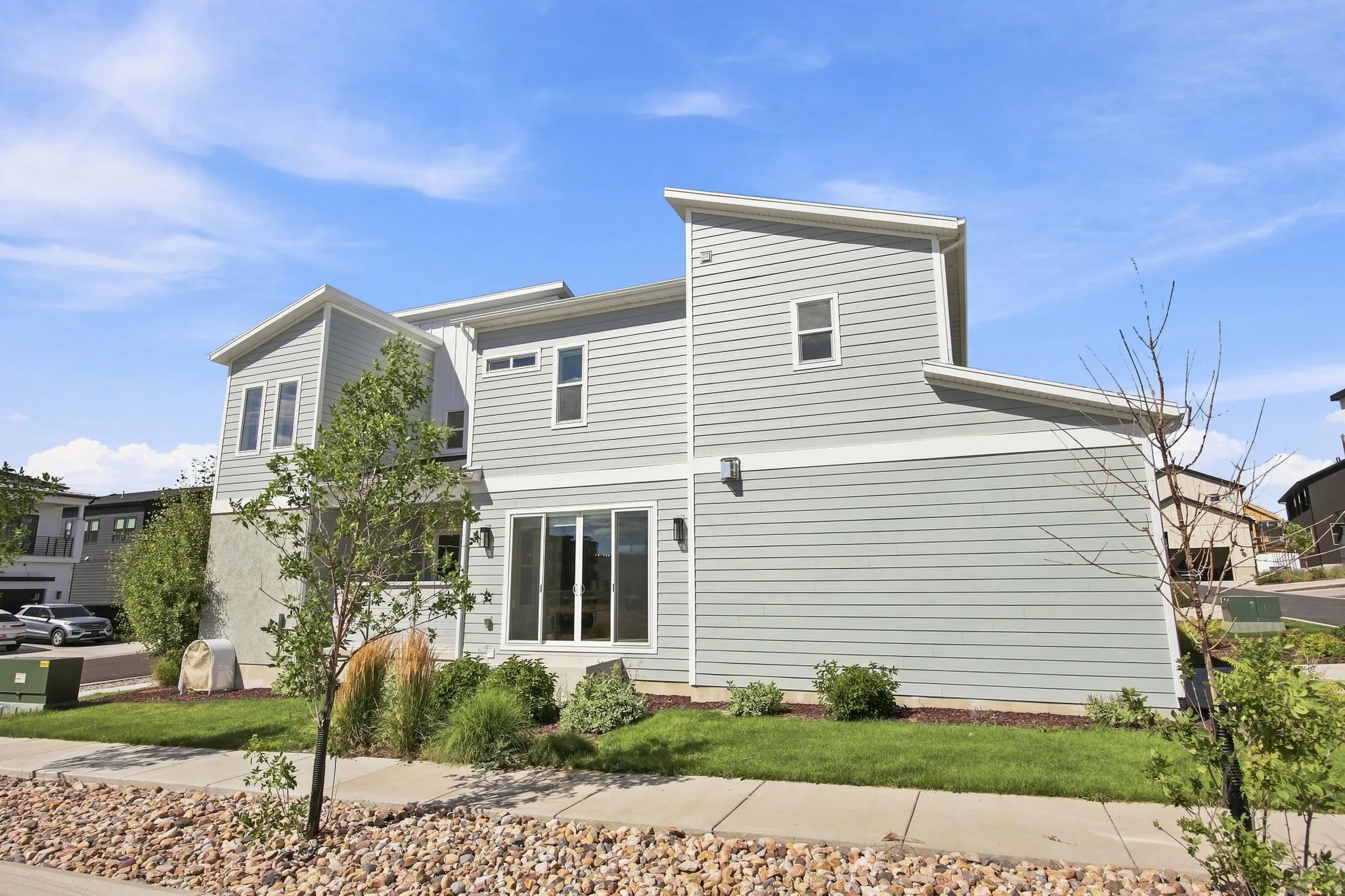 Modern farmhouse-style residence featuring clean white fiber cement siding, multi-level architectural design with peaked rooflines, and large multi-pane windows maximizing natural light