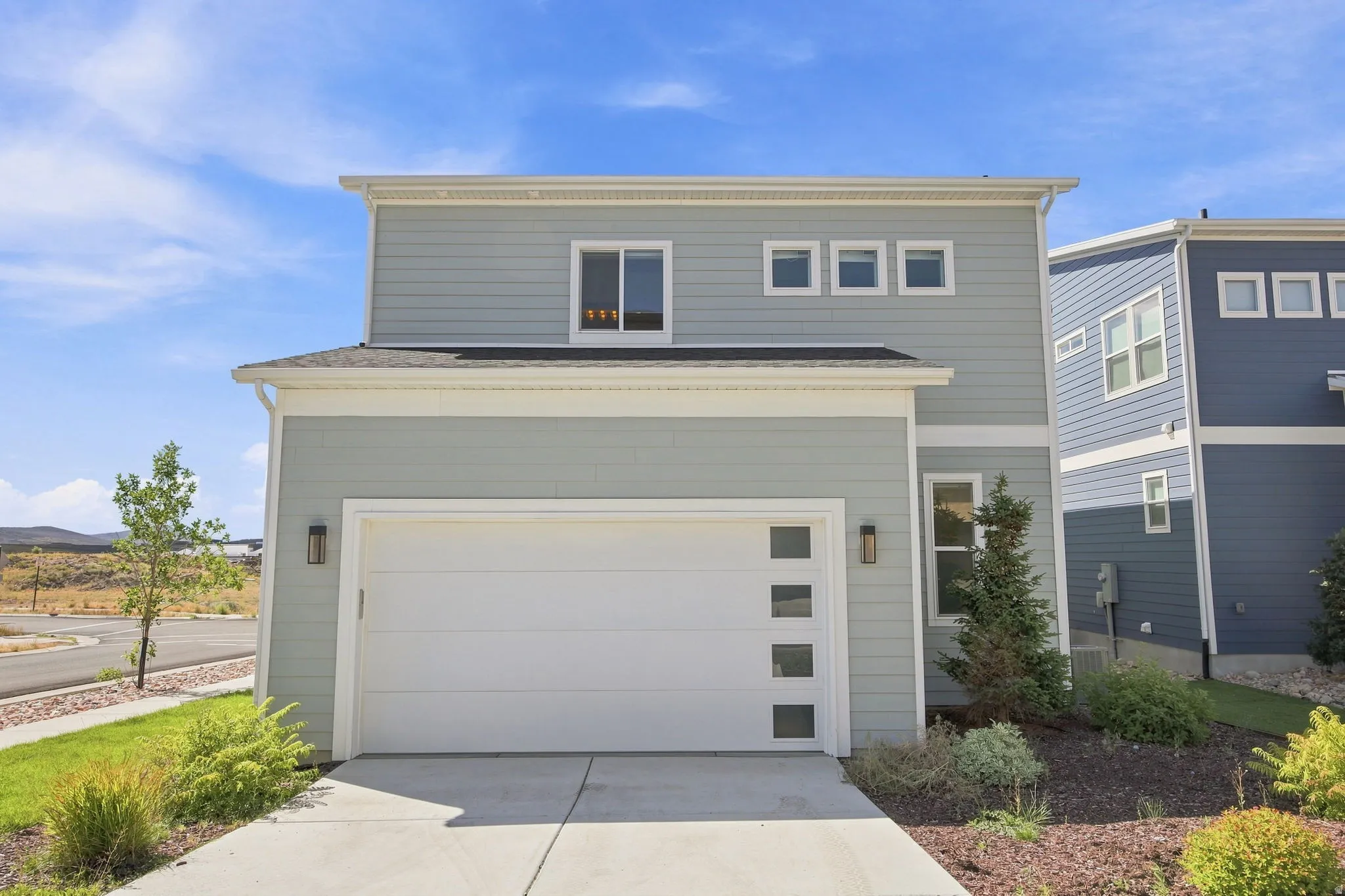 Two-story exterior with light blue siding, white trim, and a prominent attached garage
