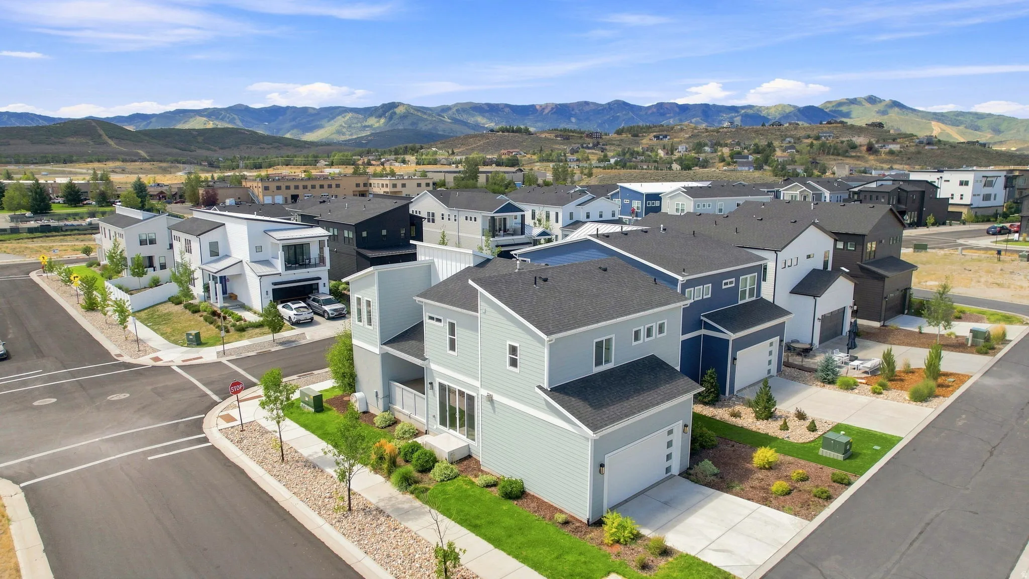 Modern residential development with mountain backdrop, featuring contemporary architectural styles, paved streets, and landscaped yards