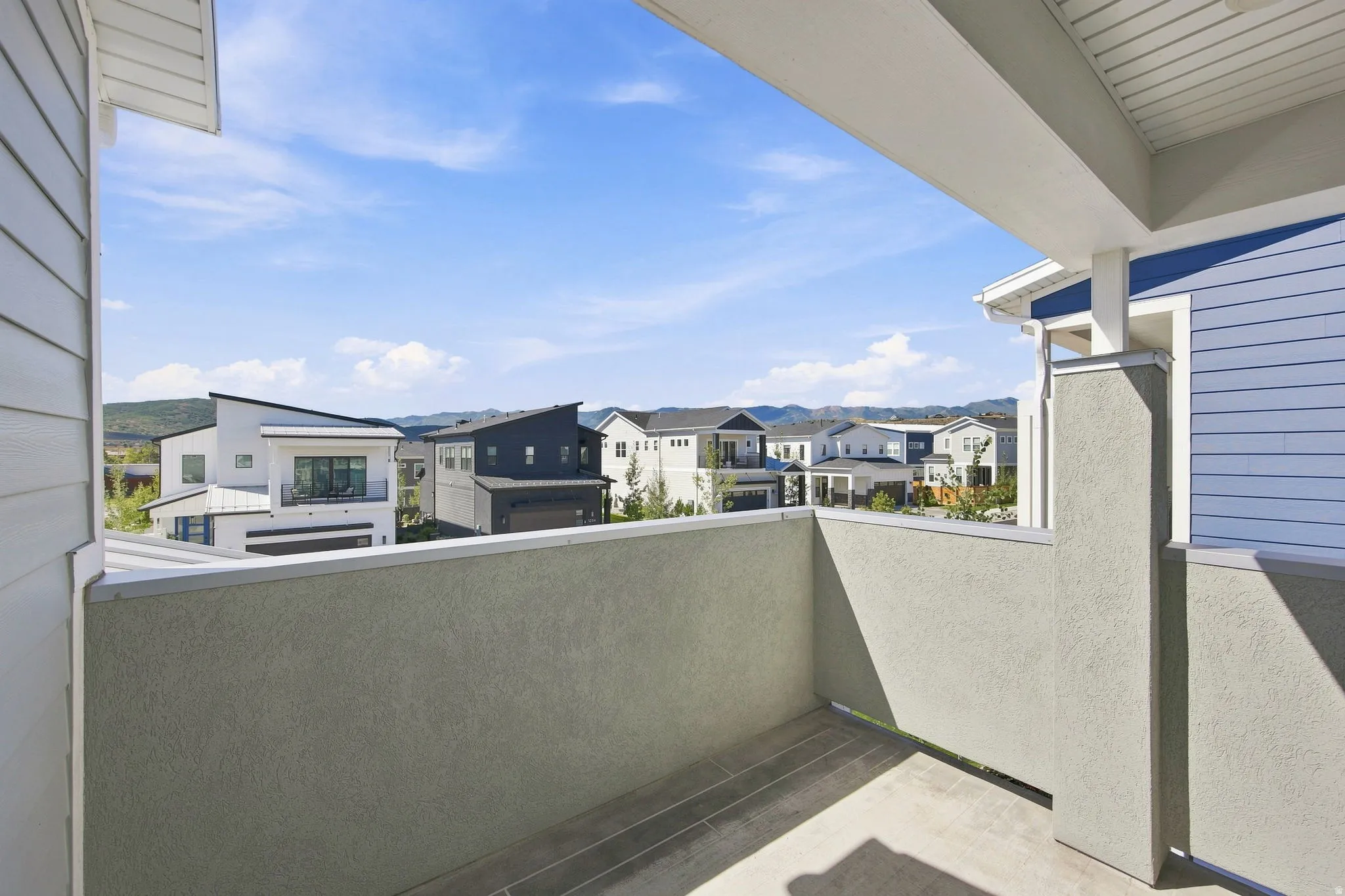 Private balcony featuring a stucco wall and concrete flooring