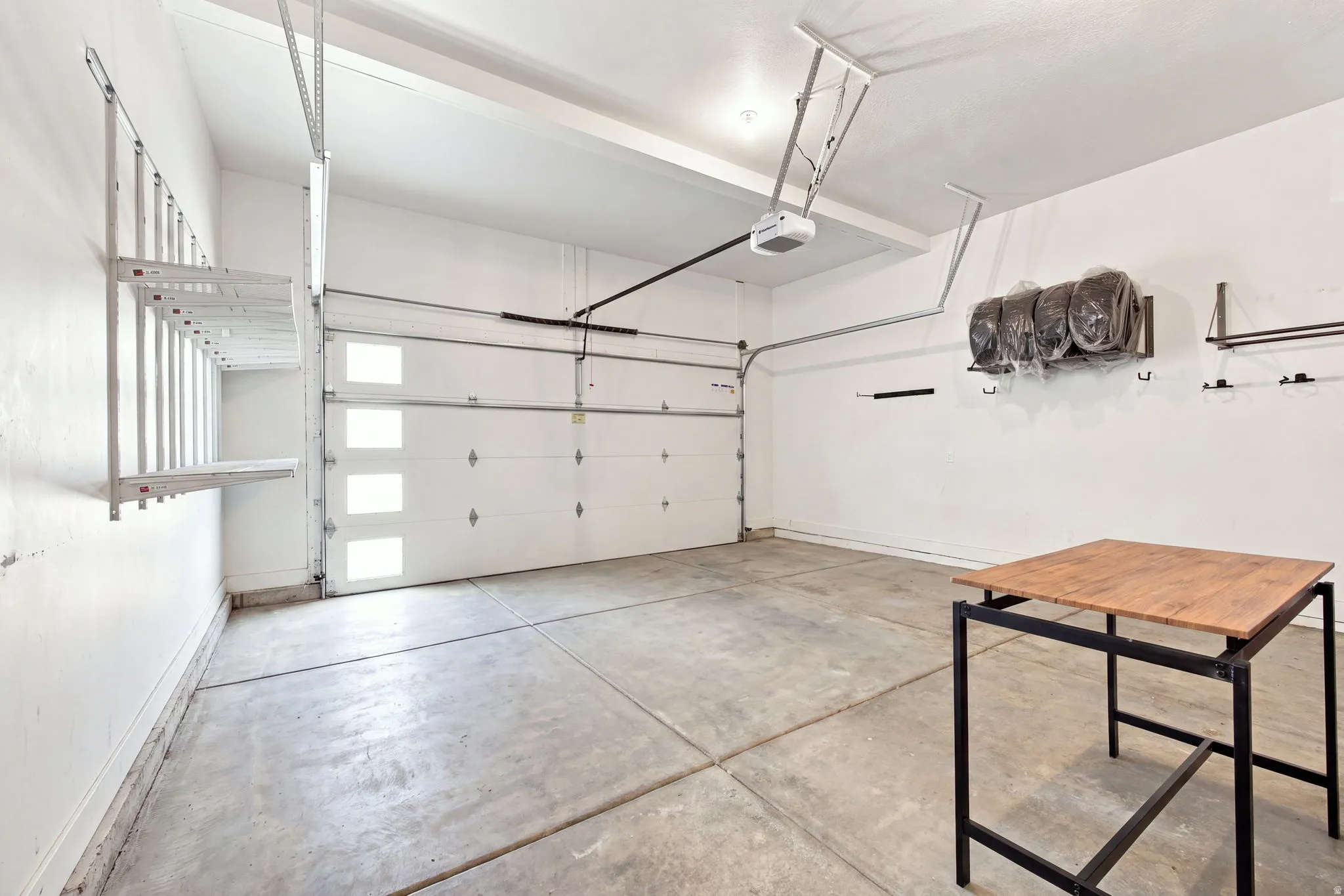 Concrete flooring, white walls, built-in shelving, overhead garage door, built-in wall storage