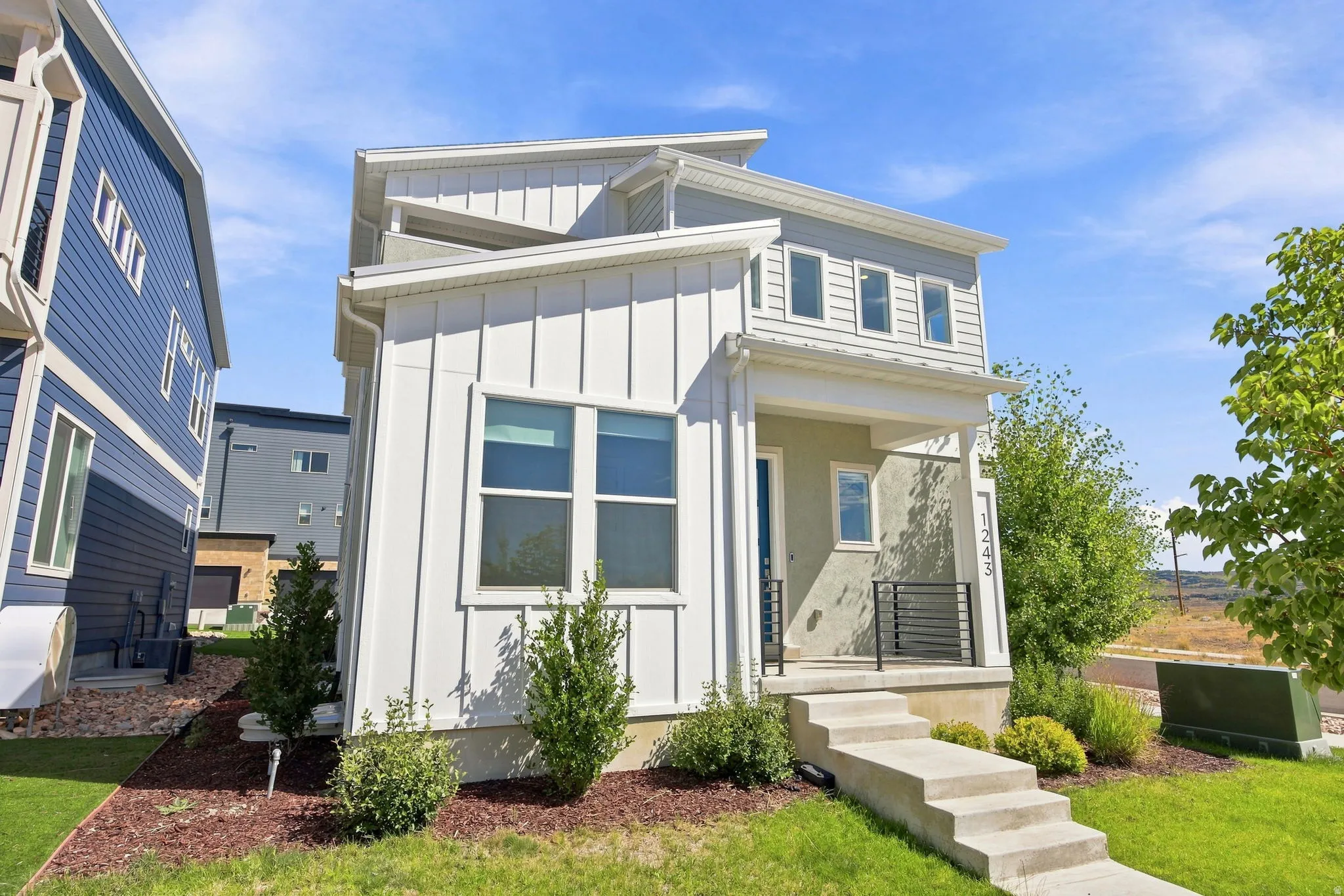 Modern exterior with vertical board and batten siding, multi-pane windows, a covered entry, and concrete steps