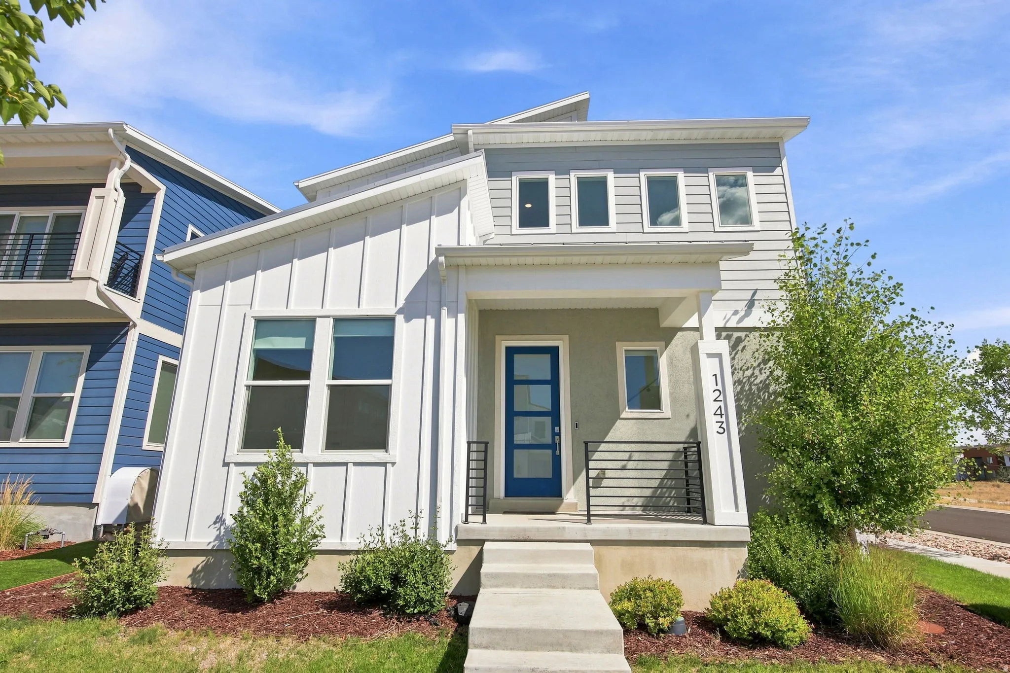 Modern exterior with a contrasting blue entry door, concrete front steps, and a covered porch