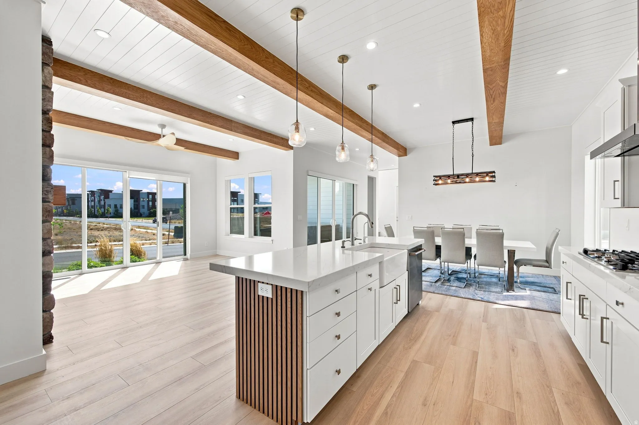 Open-concept kitchen and living area with wood-finish flooring, exposed ceiling beams, and white shiplap ceiling