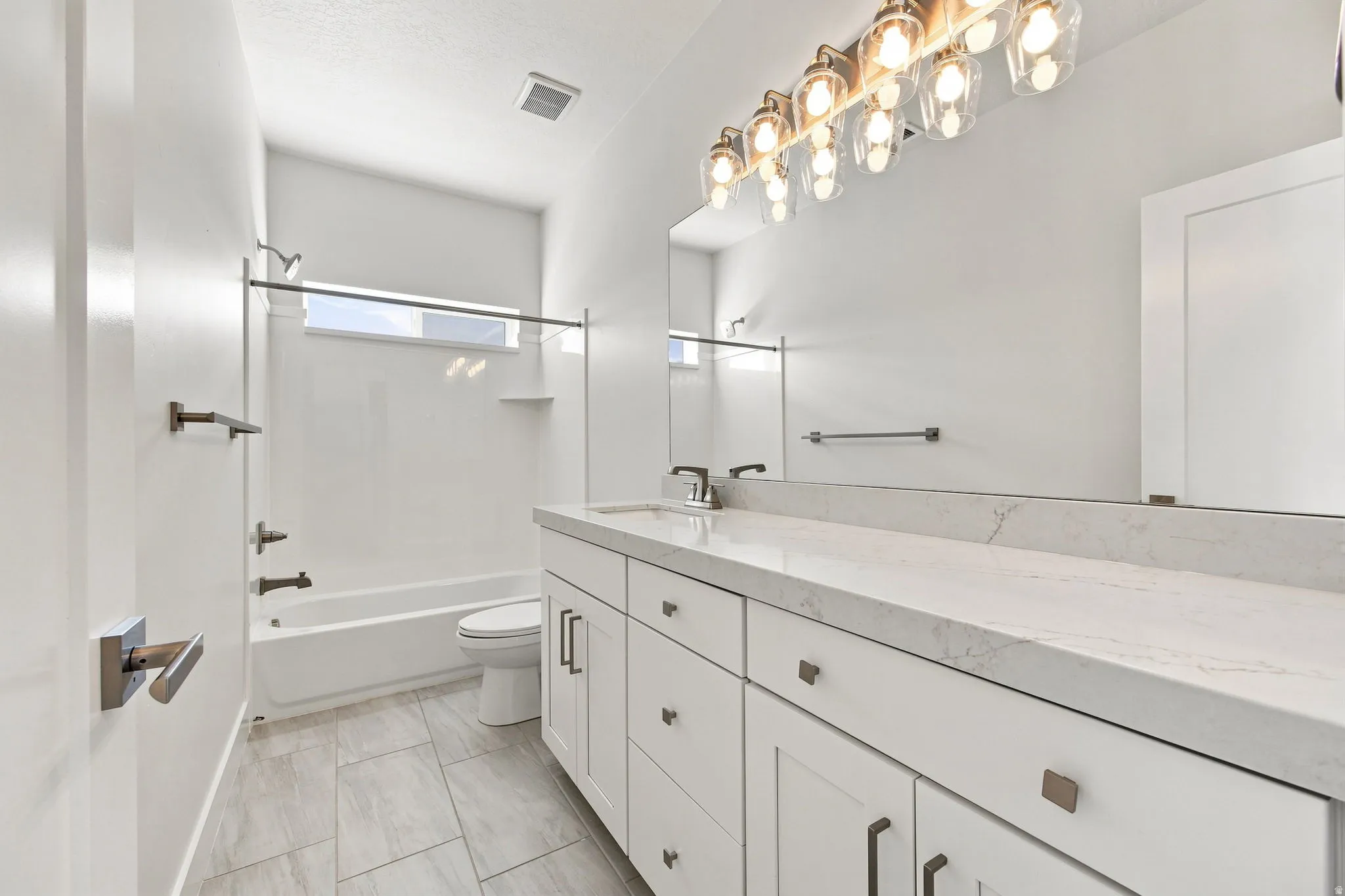 White vanity with multiple storage drawers and cabinets, complemented by a light-toned countertop and an expansive mirror