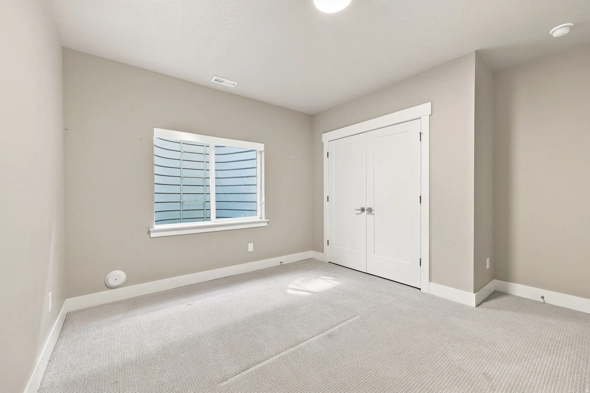 Neutral tone wall paint, white trim, light-colored carpet flooring, recessed lighting, and double doors