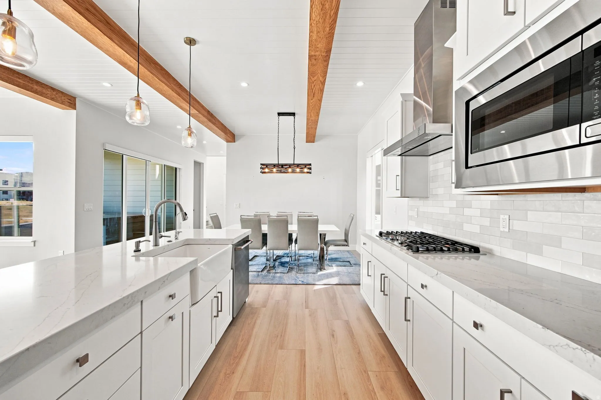 Gourmet kitchen with wood-finish flooring, white cabinetry, integrated farmhouse sink, and stainless steel appliances
