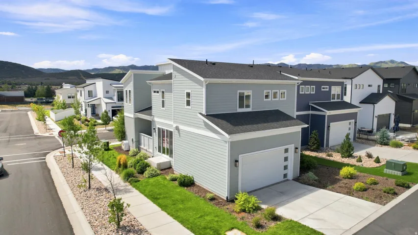 Modern exterior architecture featuring light gray siding, a black shingle roof, and a white paneled garage door
