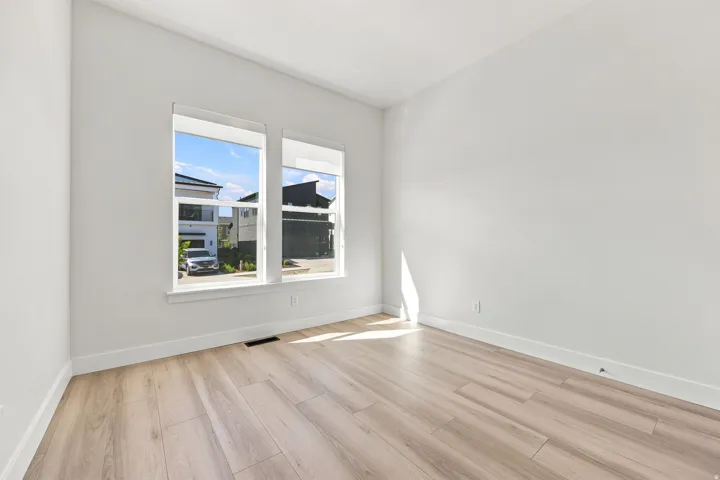 Light-filled room featuring two windows, wood-finish flooring, and white walls