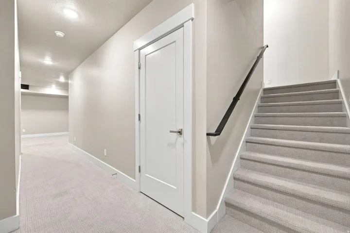 Carpeted staircase with a dark metal handrail