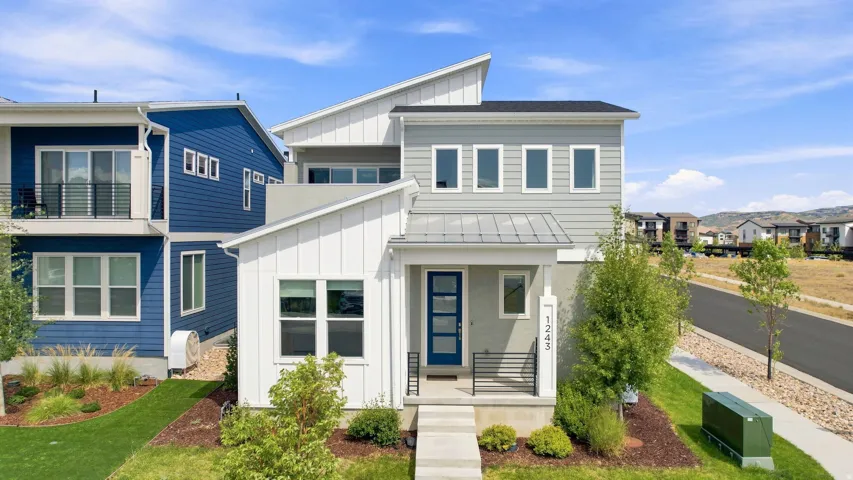 Contemporary architectural design featuring a prominent front porch, a blue entrance door, and a street-facing sidewalk