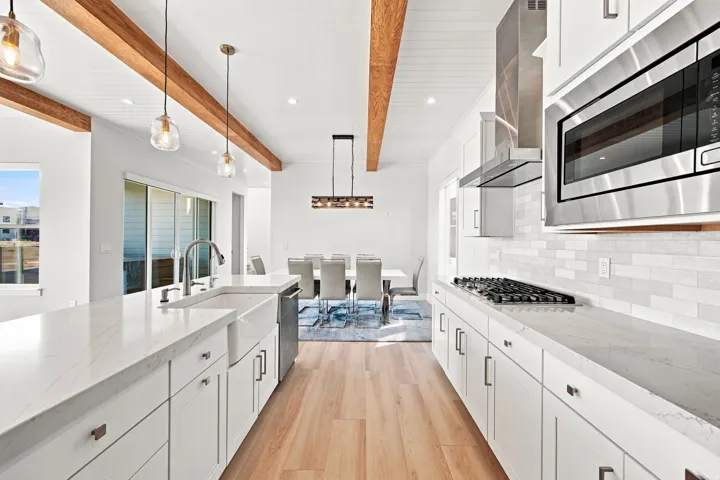 Gourmet kitchen with wood-finish flooring, white cabinetry, integrated farmhouse sink, and stainless steel appliances