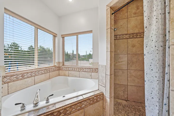 Primary bathroom jetted tub and full travertine shower.