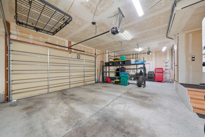 Spacious 3 car garage with built-in storage cabinets, workbench and overhead storage shelving.