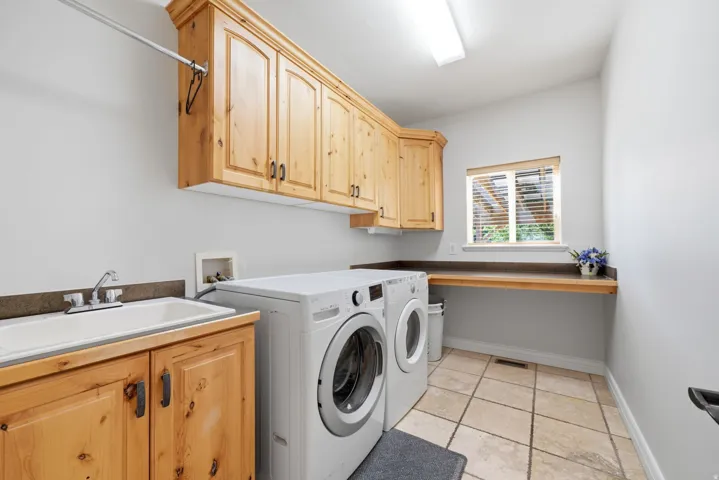 Large spacious Laundry room with built-in cabinets, a utility sink, and tile flooring