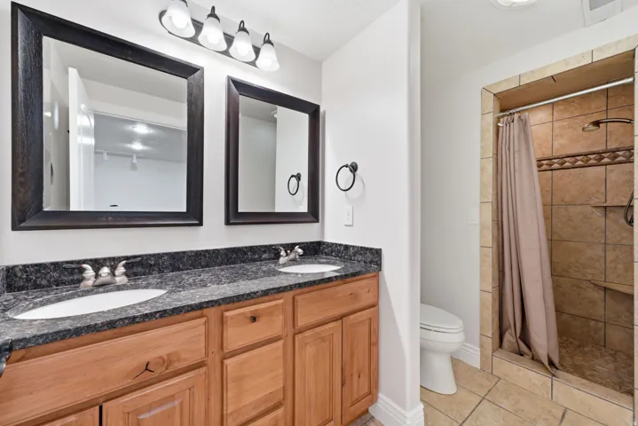 Dual granite vanity with travertine shower.