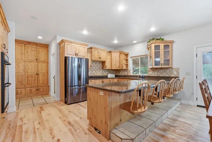 Large open kitchen with custom cabinets, granite countertops and gas stovetop.
