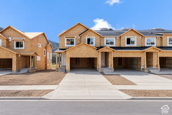 Multi-unit wood-frame construction featuring gabled rooflines, attached garage bays, concrete driveways, and installed multi-pane windows