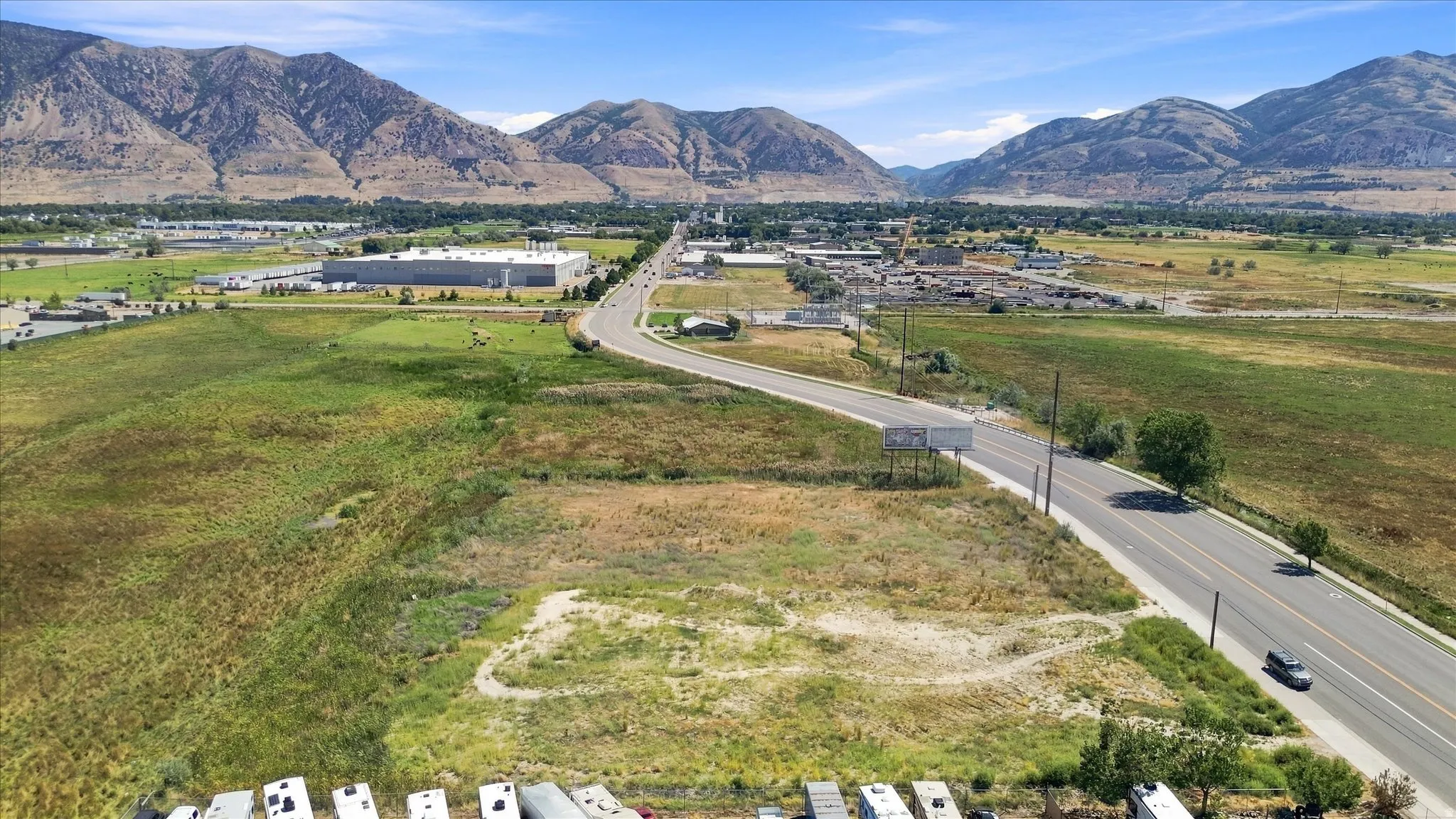 Expansive open land with a paved road running alongside, set against a backdrop of distant mountains