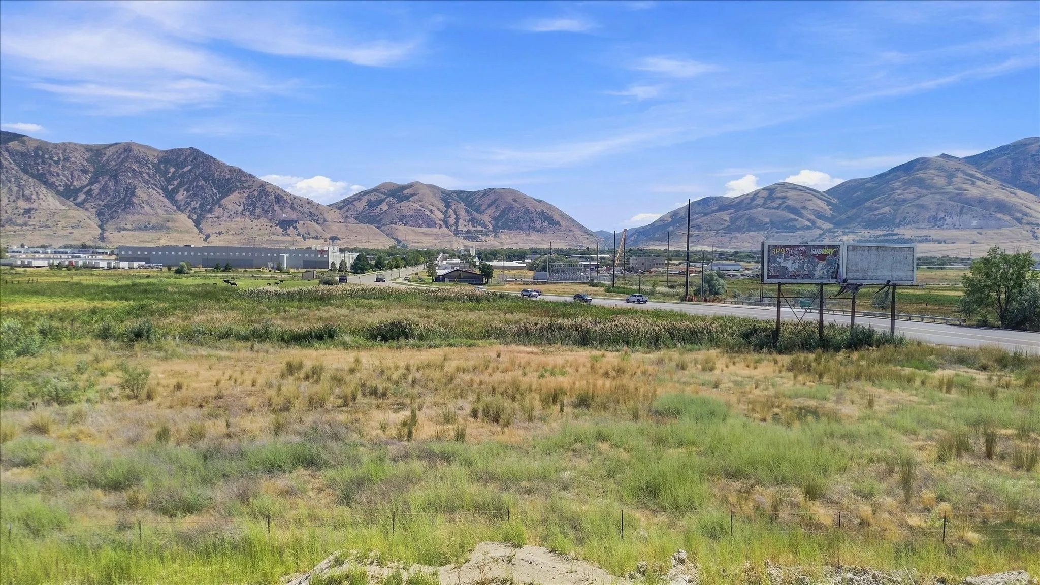 Expansive open land with distant mountain ranges and a visible roadway
