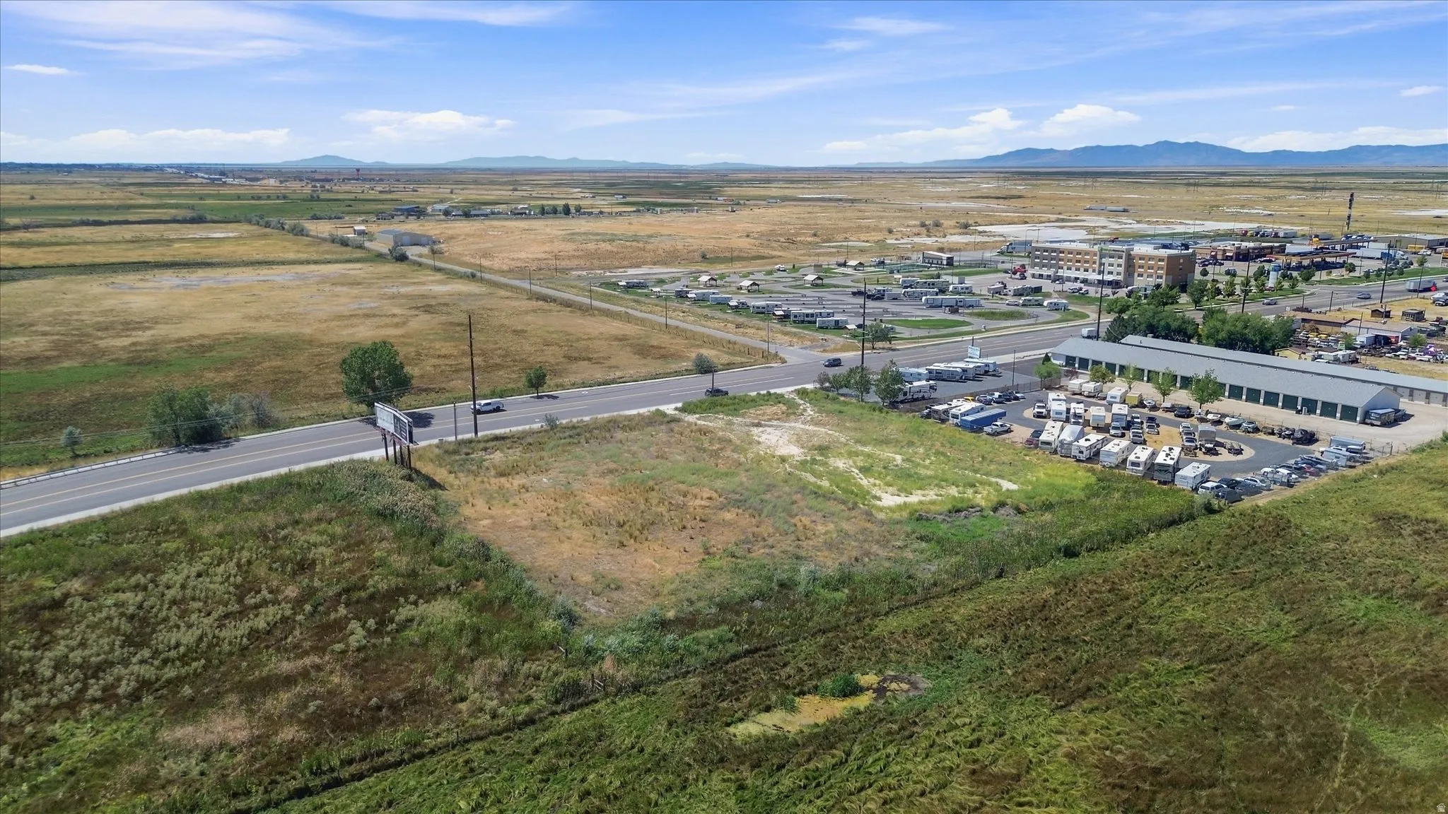 Expansive land parcel with direct road frontage, surrounded by open fields and distant mountains
