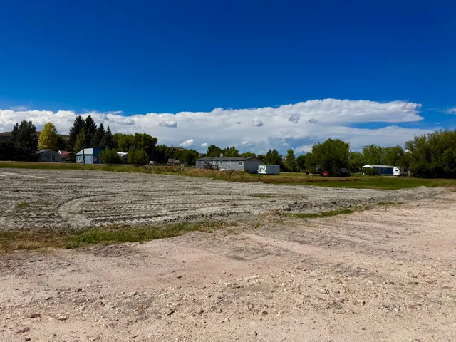 Expansive land plot featuring a graded surface and surrounding mature trees