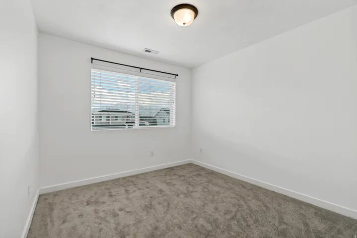 Window with blinds, wall-to-wall carpeting, and a ceiling-mounted light fixture
