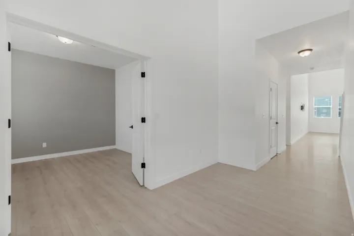 High ceilings, wood-finish flooring, white walls, gray accent wall, and recessed lighting