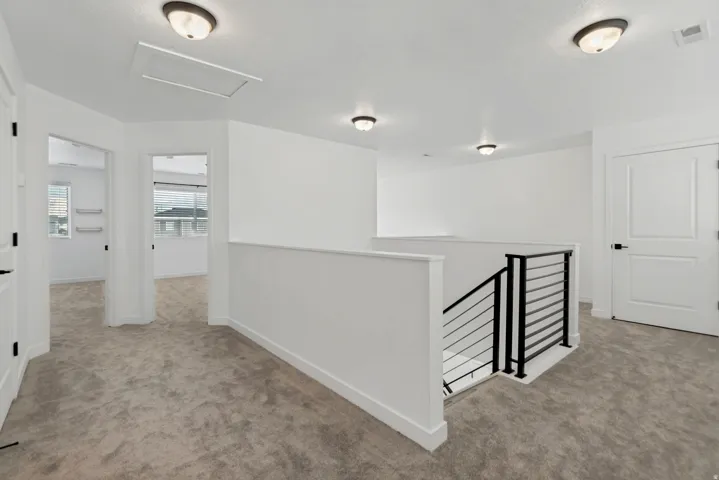 Open landing featuring carpet flooring, crisp white walls, and a contemporary railing with black metal spindles