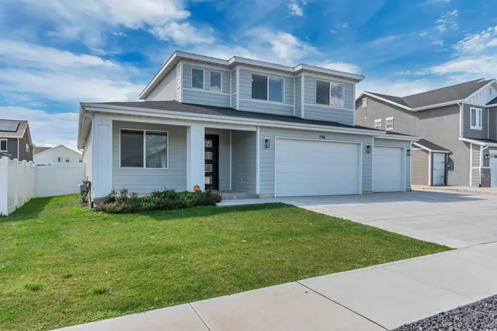 Two-story exterior with light blue siding, white trim, a multi-car garage, and a concrete driveway