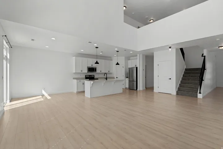Open-concept living area featuring light wood-finish flooring, recessed ceiling lighting, and abundant natural light from large windows