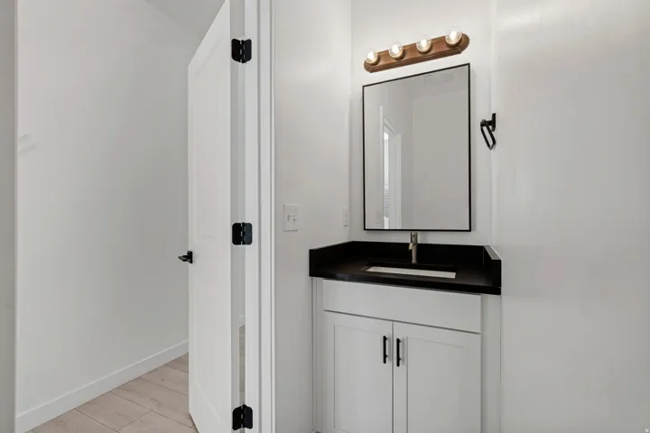White vanity with dark countertop, rectangular sink, and single-handle faucet