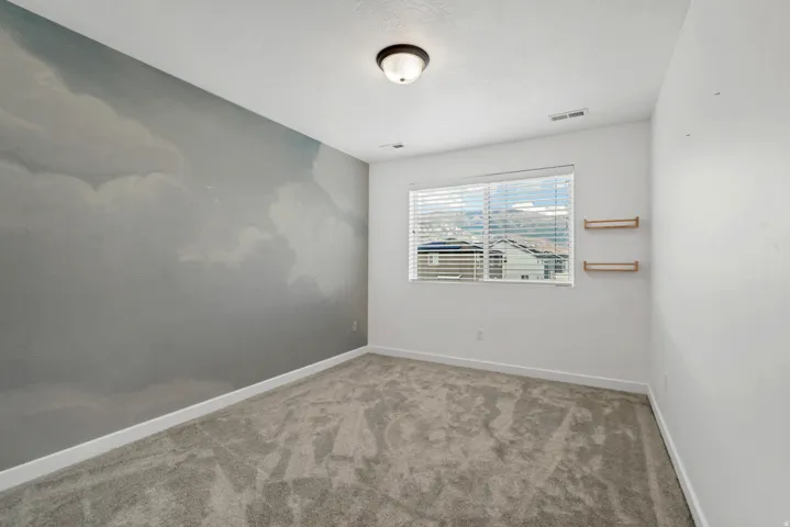 Carpeted flooring, window with blinds, flush mount ceiling light, cloud-patterned accent wall