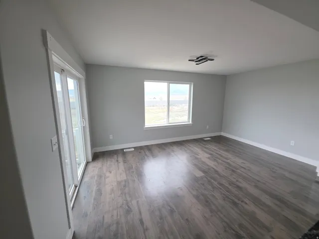 Wood-finish flooring, white trim, sliding glass door, modern ceiling fixture, and a large window