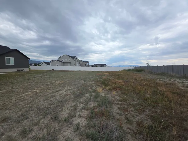 Expansive lot featuring a concrete perimeter fence and surrounding residential properties
