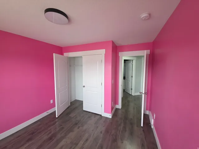 Wood-finish flooring with white trim, built-in closet with wire shelving, and a flush-mount ceiling light