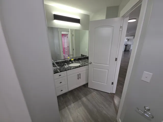 Vanity with a black stone countertop, integrated basin, and white cabinetry