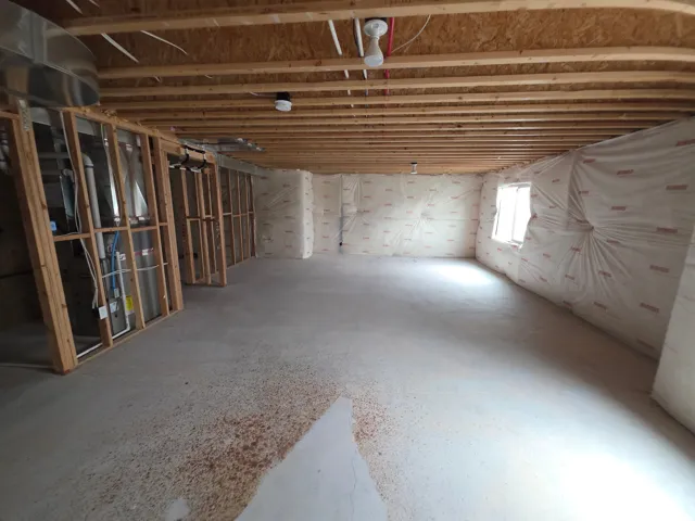Unfinished concrete flooring with exposed joists, framed wall sections, and exterior wall insulation