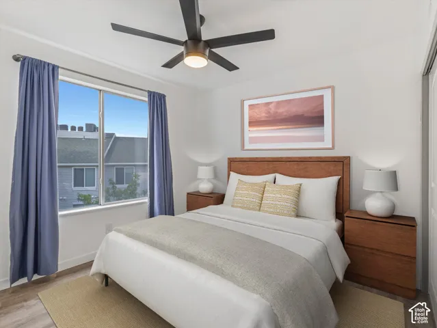 White walls, a multi-pane window, wood-finish flooring, and a ceiling fan with integrated lighting