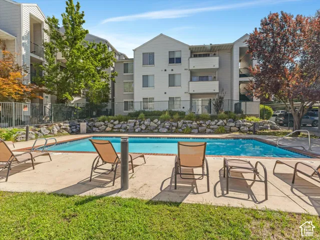 Community swimming pool with concrete surround, wrought iron fencing, and rock landscaping