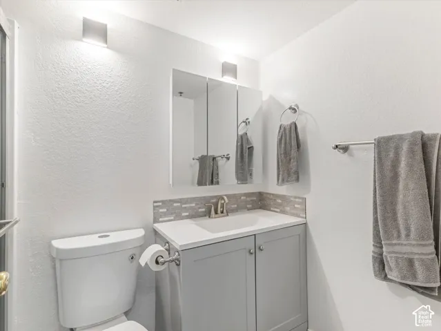 Vanity with a white countertop and gray cabinetry, complemented by a mosaic tile backsplash