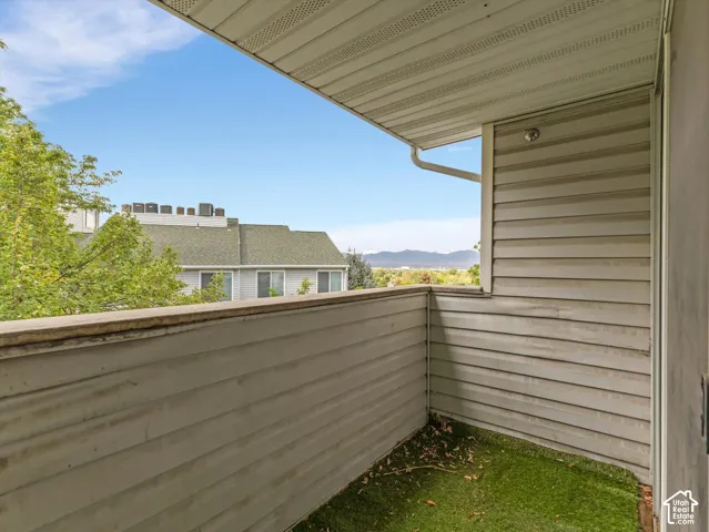 Balcony with artificial turf flooring, light-toned horizontal siding, and a partial mountain backdrop