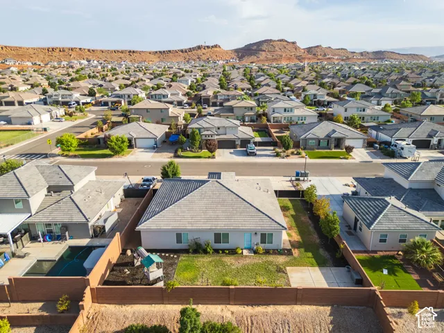 Residential neighborhood with diverse home styles, paved streets, and a backdrop of red rock formations