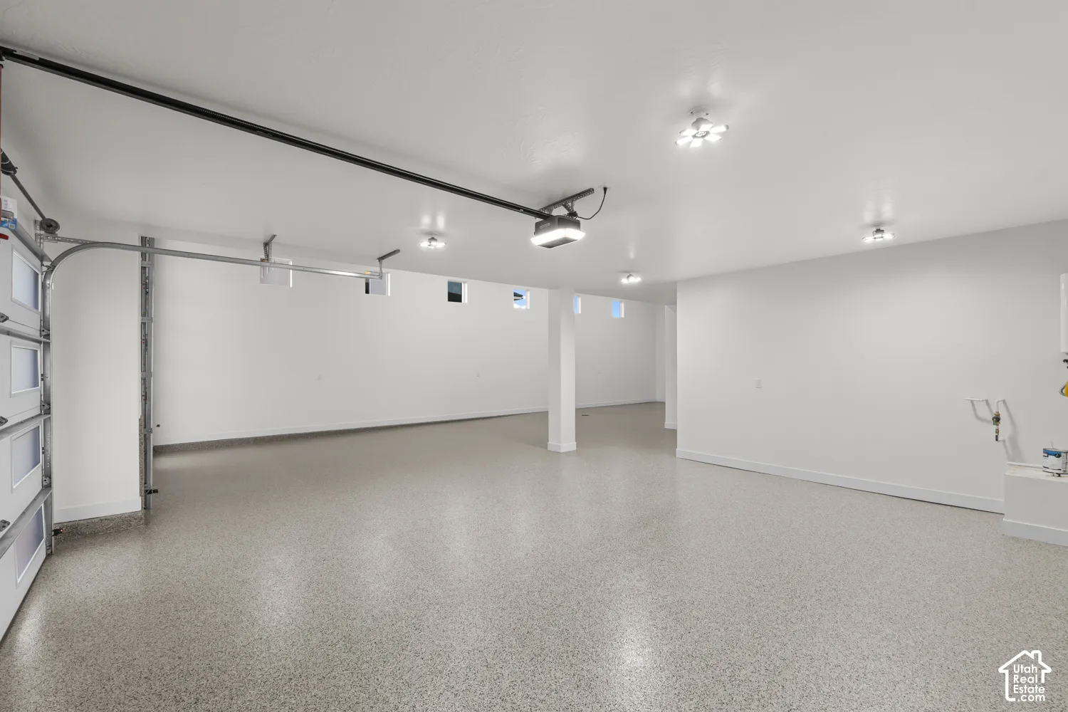 Spacious garage with epoxy flooring, multiple recessed light fixtures, and a white overhead garage door