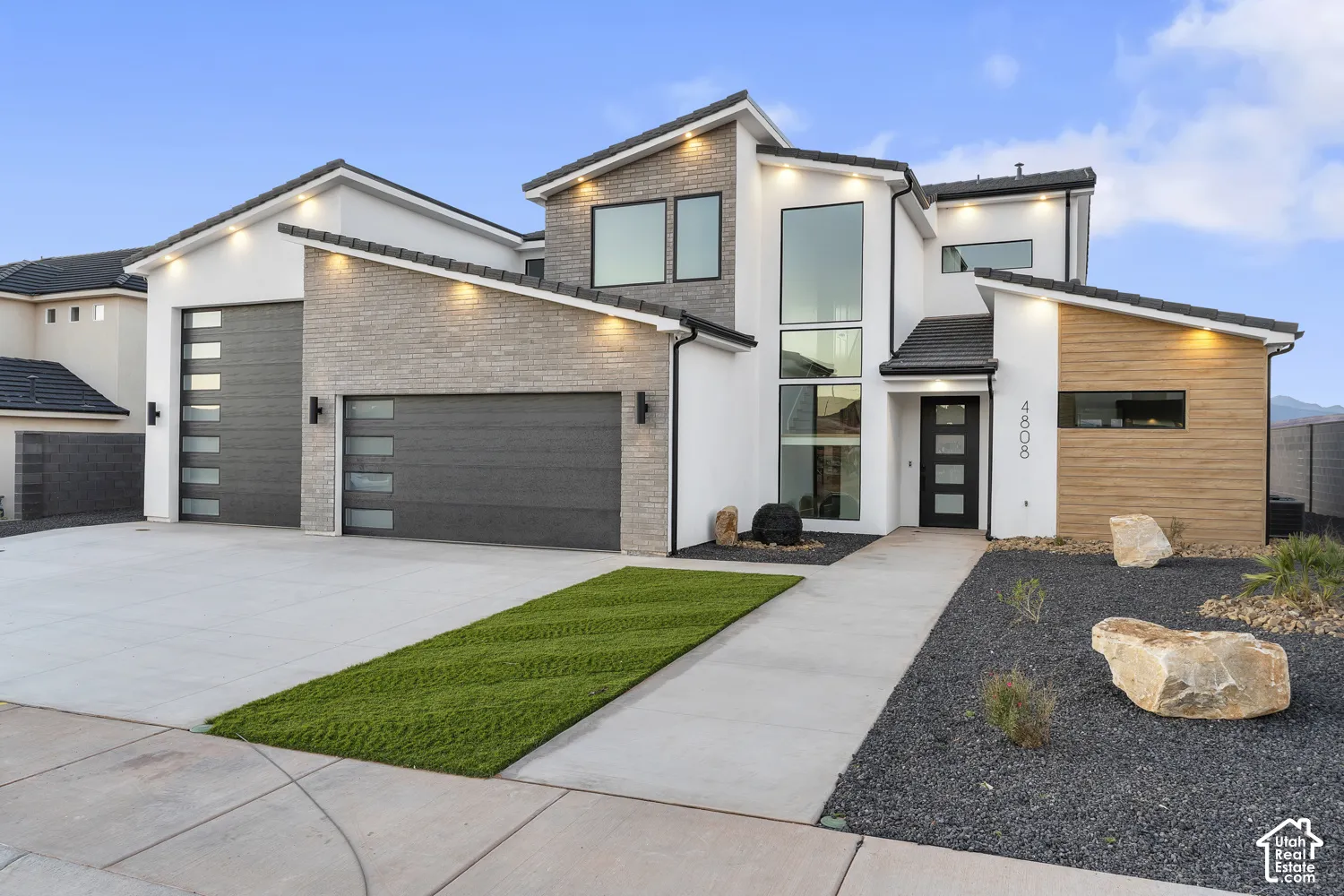 Contemporary exterior featuring a stone facade, wood-finish accent paneling, and large format windows